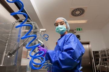 A young woman works in a hospital as a  medical hygiene assistant. She is dressed  in special medical hygiene clothing and  carries out hygiene disinfecting and logistic tasks.