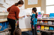 © Lucy Schaeffer - Girl solving math problem with teacher