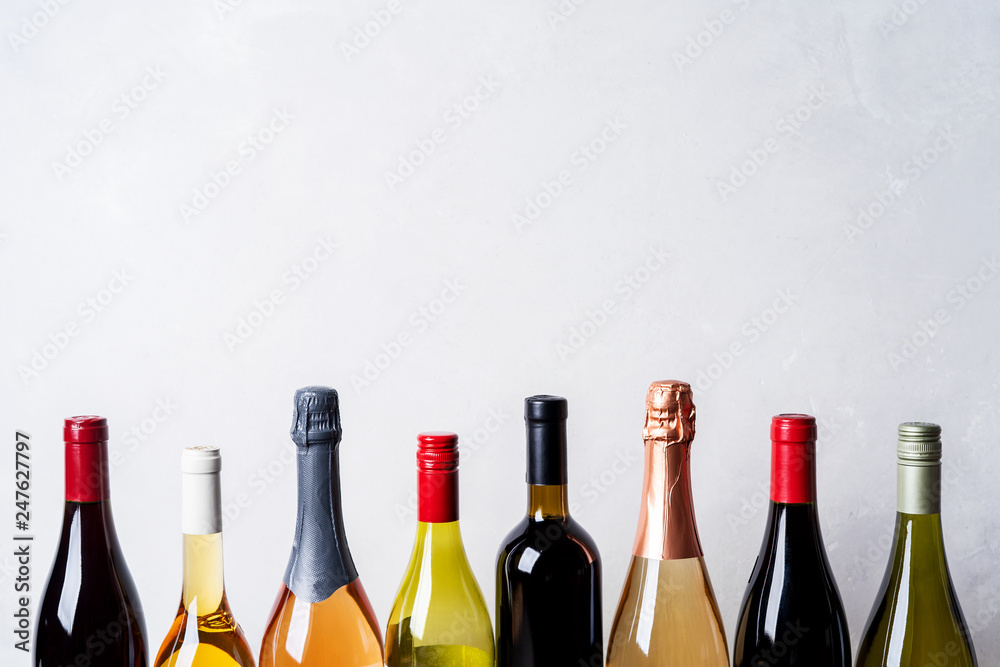 Tops from different kinds new bottles of champagne, white, red wine on light background - obrazy, fototapety, plakaty 