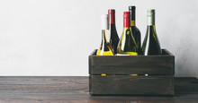 Set Of Different Kinds Bottles Of Champagne, White, Red Wine In Wooden Box On Light Background