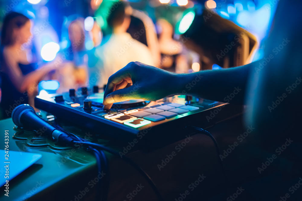 DJ plays live set and mixing music on turntable console at stage in the night club. Disc Jokey Hands on a sound mixer station at club party. DJ mixer controller panel for playing music and partying. - obrazy, fototapety, plakaty 