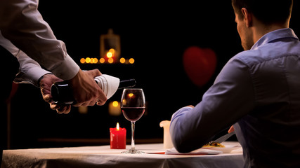 Waiter pouring male customer high-quality red wine, tasty dinner in restaurant