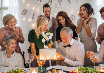 A senior man with multigeneration family celebrating birthday on indoor party.