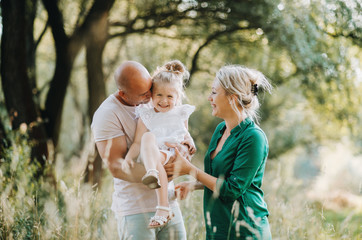 Young family with a small daughter in sunny summer nature.