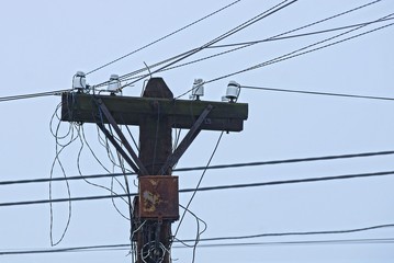 one old gray wooden pole and electrical wires against the sky