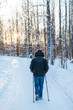 Photo of a man doing nordic walking in the sunlit forest on fresh powder snow, frosty weather, outdoor activities/ sunset in the background, winter sports/ healthy lifestyle and sport concept.