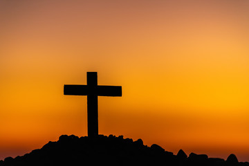 Wall Mural - The silhouette of the cross across the mountain at sunset