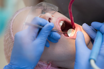 Close-up portrait of a female patient at dentist in the clinic. There are specialized equipment to treat all types of dental diseases in the office.