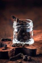 Fragrant Long Pepper Spilling Out Of Glass Jar, Vintage Kitchen Table Background, Selective Focus Vertical Image