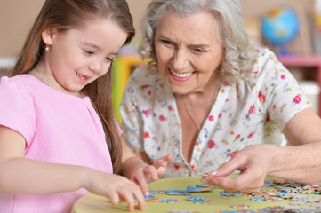 Sticker - Cute little granddaughter and grandmother collecting puzzles