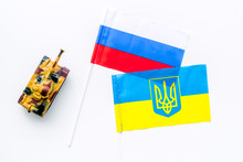 War, Confrontation Concept. Russia, Ukraine. Tanks Toy Near Russian And Ukrainianflag On White Background Top View