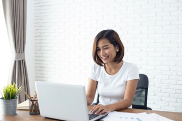 young asian woman working  laptop computer on wood desk in Home office