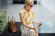 © LUMINA IMAGES - Beautiful elegant Caucasian blonde  woman sitting outdoors and using her tablet.