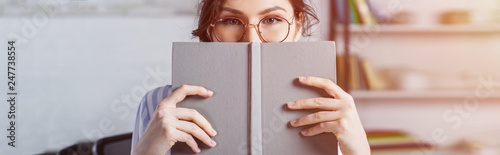 Cuadros en Lienzo woman in glasses covering face with book