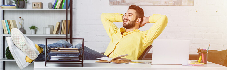 Wall Mural - Bearded businessman with crossed arms relaxing and looking away at workplace