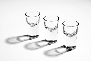 Monochrome image of three empty shot glasses, back lit, with hard reflections