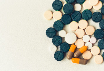 Medicine green, pink and yellow pills or capsules on white background with copy space. Drug prescription for treatment medication closeup top view.