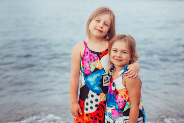 Two adorable sisters playing and having fun on the beach. Childhood, vacation, joy, happiness, frienship concept