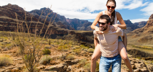 travel, tourism and people concept - happy couple having fun in summer over grand canyon national park background