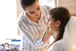 © Pixel-Shot - Professional makeup artist working with young bride at home