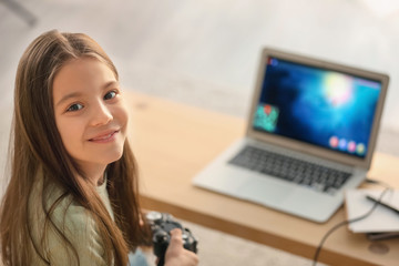 Wall Mural - Cute little girl playing computer game at home