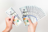 Fototapeta  - Closeup up view of white female hands holding many 100 dollars paper bills isolated on white background. Horizontal color photography.