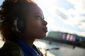 Wall Mural - Beautiful black woman wearing headphones in urban city setting during sunrise