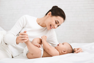 mother playing with her baby in bedroom.