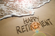 Happy Retirement message handwritten on smooth sand beach with gentle wave