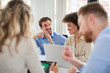 © nenadaksic - Small group of business people sitting at table and having meeting. Multi cultural group. Selective focus on mixed race woman.