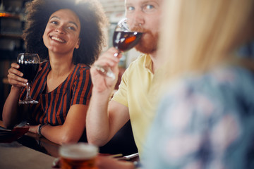 Wall Mural - Friends chatting and drinking alcohol while  sitting at restaurant. Multi ethnic group.