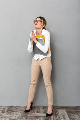 Canvas Print - Full length photo of caucasian businesswoman wearing glasses holding paper folders in the office, isolated over gray background