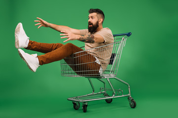 Sticker - excited man gesturing and sitting in shopping cart isolated on green