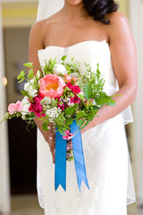 Wall Mural - bride holding her wedding bouquet of flowers with blue ribbons and pink and red flowers