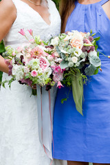 Wall Mural - bride and bridesmaid  holding their wedding bouquet of flowers with grey and green ribbons and pink and purple flowers