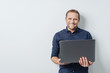 © contrastwerkstatt - Attractive friendly man holding an open laptop