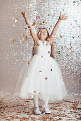 cute little child girl in princess dress on confetti background with silver bokeh. birtday party