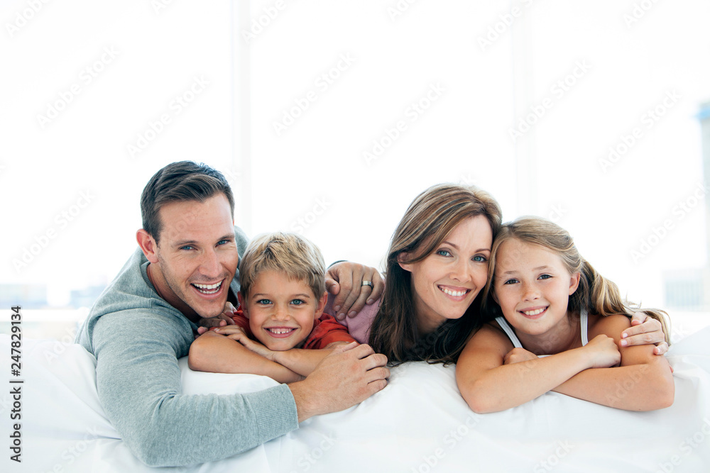 happy family with two children lying down and looking at camera - portrait - obrazy, fototapety, plakaty 