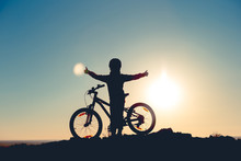 Silhouette Of A Little Girl With A Bicycle At Sunset