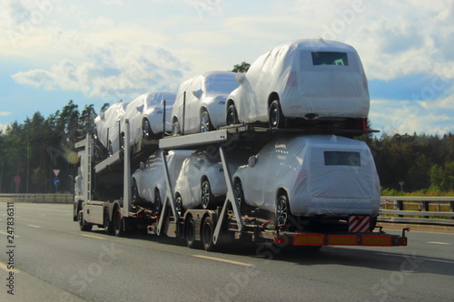 Heavy Car Carrier Truck Transports New Cars In Protective Covers On Heavy Car Carrier Truck Transports New Cars In Protective Covers On Semi Trailer Suburban