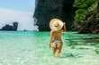 © naproadavida_npv - Young woman at an amazing beach in Thailand with beautiful rocks on the background. Green water and rocky mountains and blue sky. A creative hat with the name of the country Thailand.