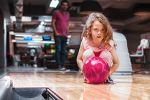 Father And Daughter Having Fun At Bowling Alley. Proud Father Watching His Little Daughter Bowling.