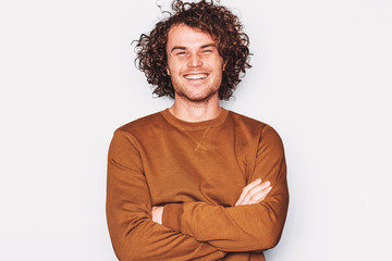 Studio horizontal portrait of happy good-looking male smile broadly, posing for advertisement wears brown pullover, isolated on white wall with copy space for your promotion text. People, emotion