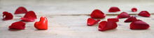 Red Heart Made From Glass And Rose Petals On A Rustic Wooden Board, Love Concept With Copy Space, In Panoramic Banner Format