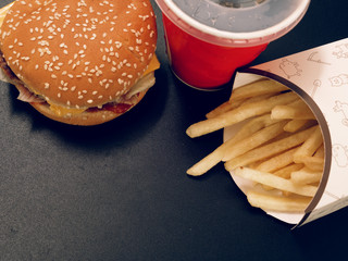 drink and french fries and burger on a dark background.