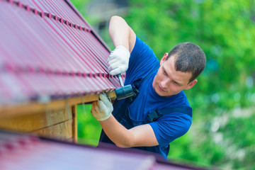 horizontal portrait of a man with a hammer repairing the roof of the house, shooting outdoors