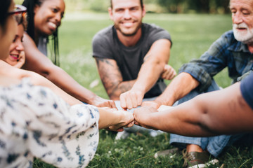 happy people stacking hands together in the park