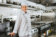 © LIGHTFIELD STUDIOS - attractive smiling female chef in uniform and hat looking at camera in restaurant kitchen with copy space
