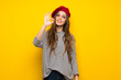 Girl with french style over yellow wall showing an ok sign with fingers