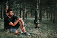 Young Man Sitting On Grass In The Woods Contemplating
